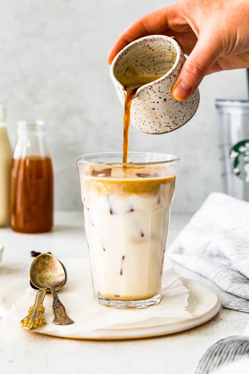 pouring espresso into glass with milk and apple syrup