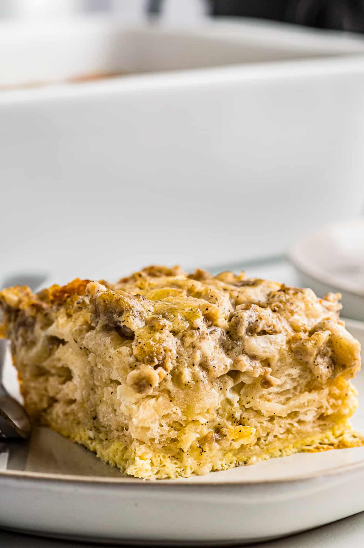 slice of biscuits and gravy casserole on a white plate with a fork