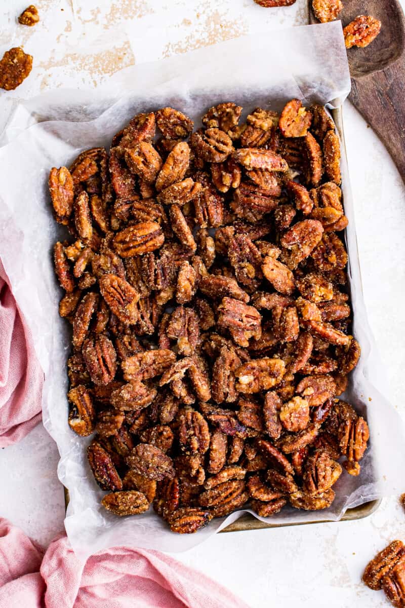 overhead image of candied pecans on a baking sheet lined with parchment paper
