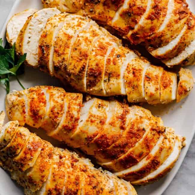 overhead sliced crockpot chicken breasts with spice rub on white plate