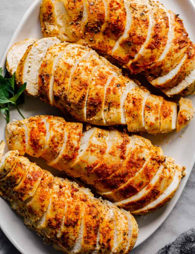 overhead sliced crockpot chicken breasts with spice rub on white plate