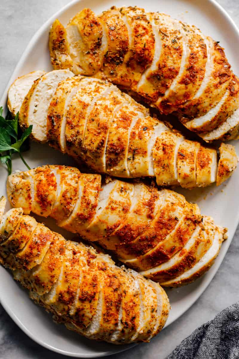 overhead sliced crockpot chicken breasts with spice rub on white plate