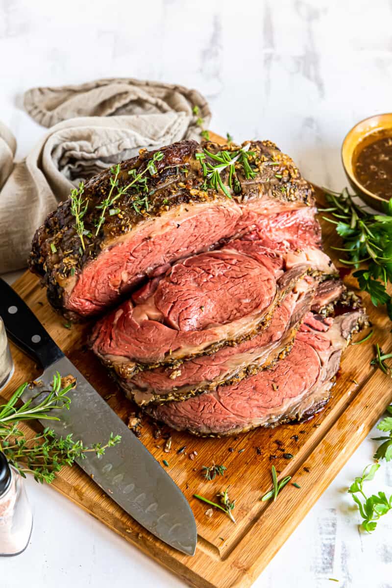 sliced garlic butter prime rib on a wood cutting board with a knife