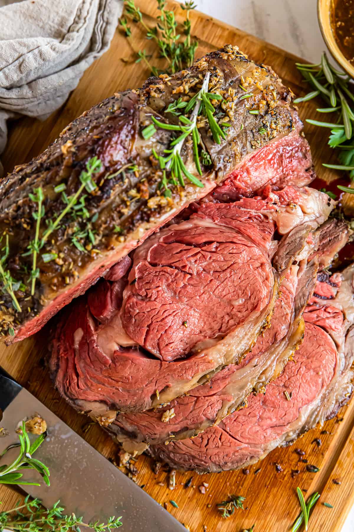 sliced garlic butter prime rib on a wood cutting board with a knife