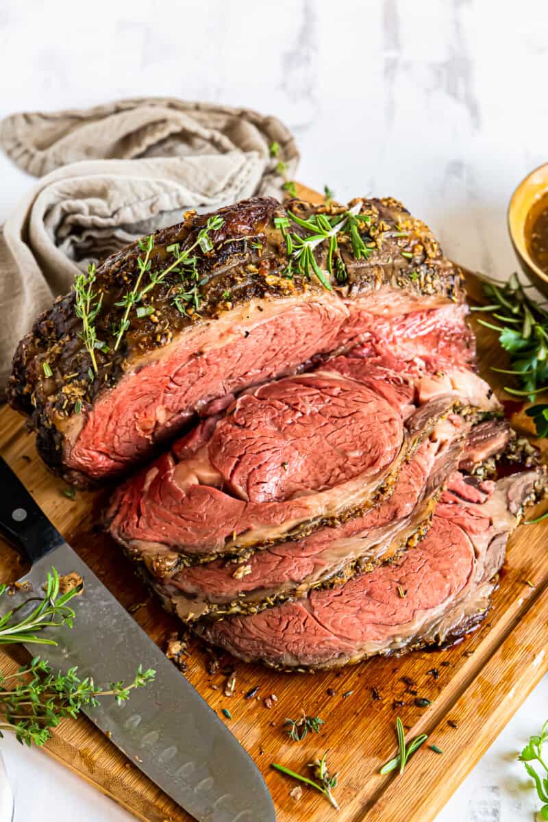 sliced garlic butter prime rib on a wood cutting board with a knife