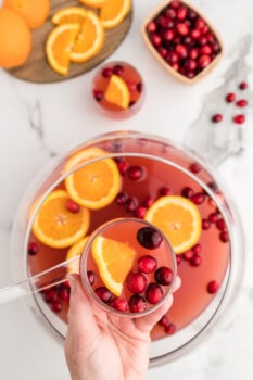 overhead image of hand holding a glass of holiday punch over a punch bowl