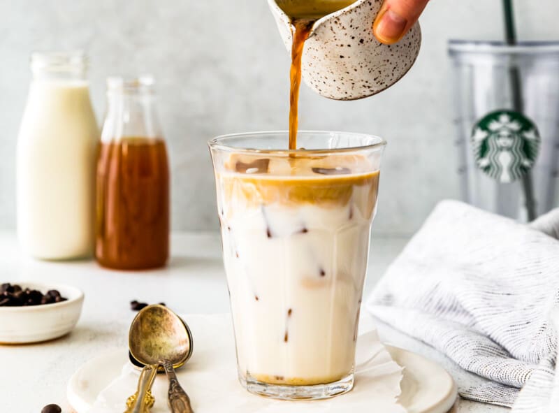 pouring espresso into glass with milk and apple syrup