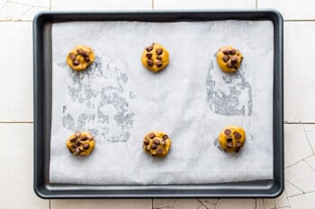 6 brown butter chocolate chip cookies on a parchment lined baking sheet before baking
