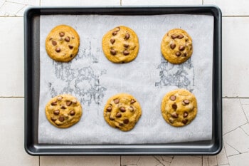 6 brown butter chocolate chip cookies on a parchment lined baking sheet after baking