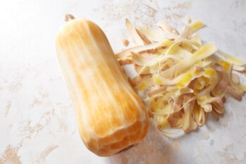 a peeled whole butternut squash on a marble table.