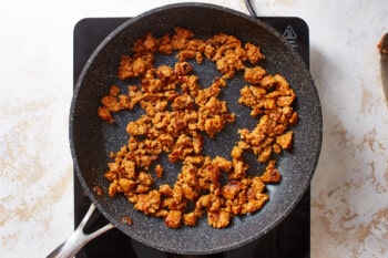 italian sausage cooking in a frying pan.