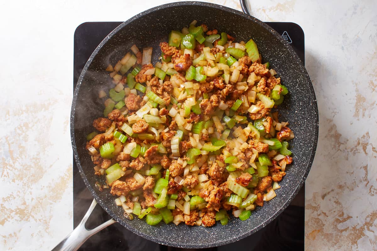 Italian sausage and veggies cooking in a frying pan.