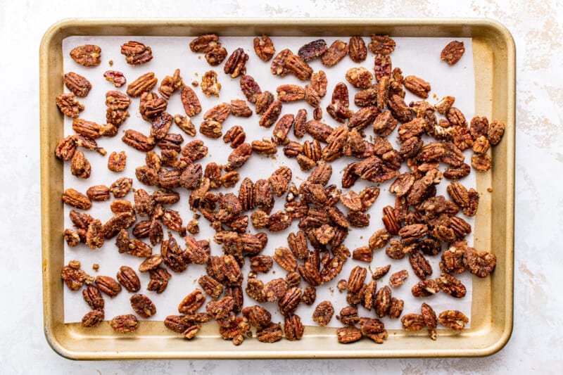 overhead image of candied pecans on a baking sheet lined with parchment paper