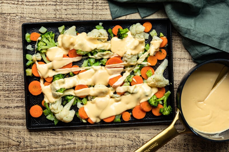 a tray of vegetables and sauce on a wooden table.