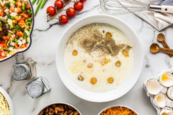 eggs, milk, sour cream, and spices in a white bowl