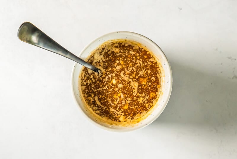 butter sauce for chex mix in a white bowl with a spoon