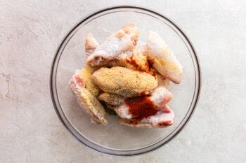 chicken wings with spices in a glass bowl before cooking