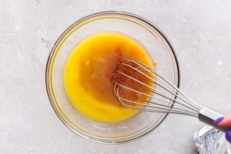 melted butter and buffalo sauce with a whisk in a glass bowl