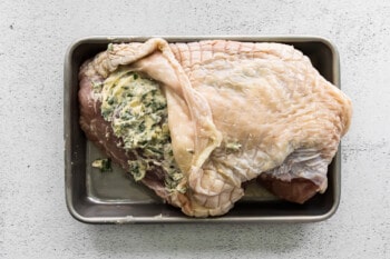 herb butter mixture rubbed onto turkey between skin and breast meat on a baking sheet