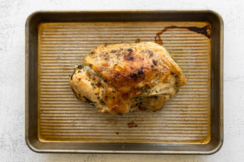 cooked turkey breast before slicing on baking sheet