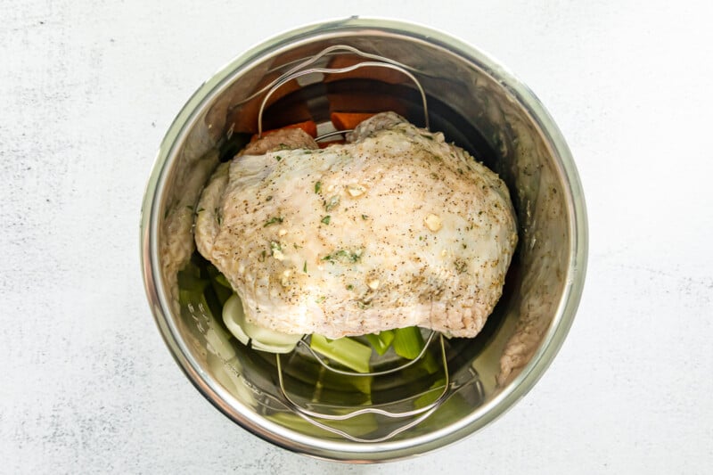 turkey breast on top of chopped vegetables in instant pot before cooking