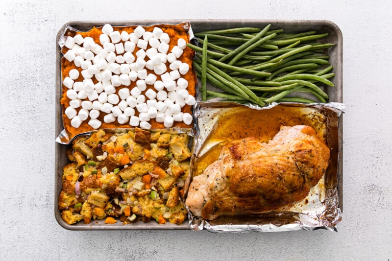sheet pan dinner with sweet potato casserole, green beans, dressing, and turkey breast before toasting marshmallows