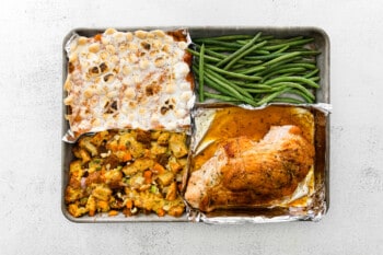sheet pan dinner with sweet potato casserole, green beans, dressing, and turkey breast