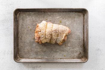 rolled up turkey breast with breadcrumb filling on a baking sheet