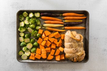 chopped vegetables and turkey roulade on a baking sheet before baking