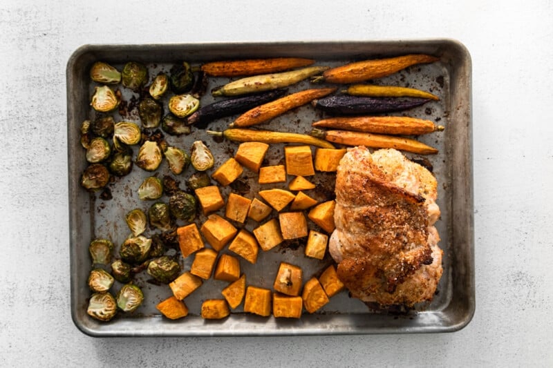 chopped vegetables and turkey roulade on a baking sheet after baking