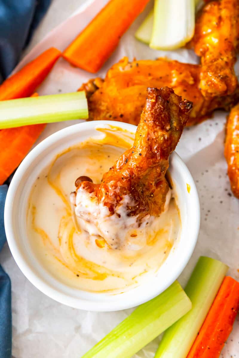 buffalo chicken wing placed in a bowl of dressing