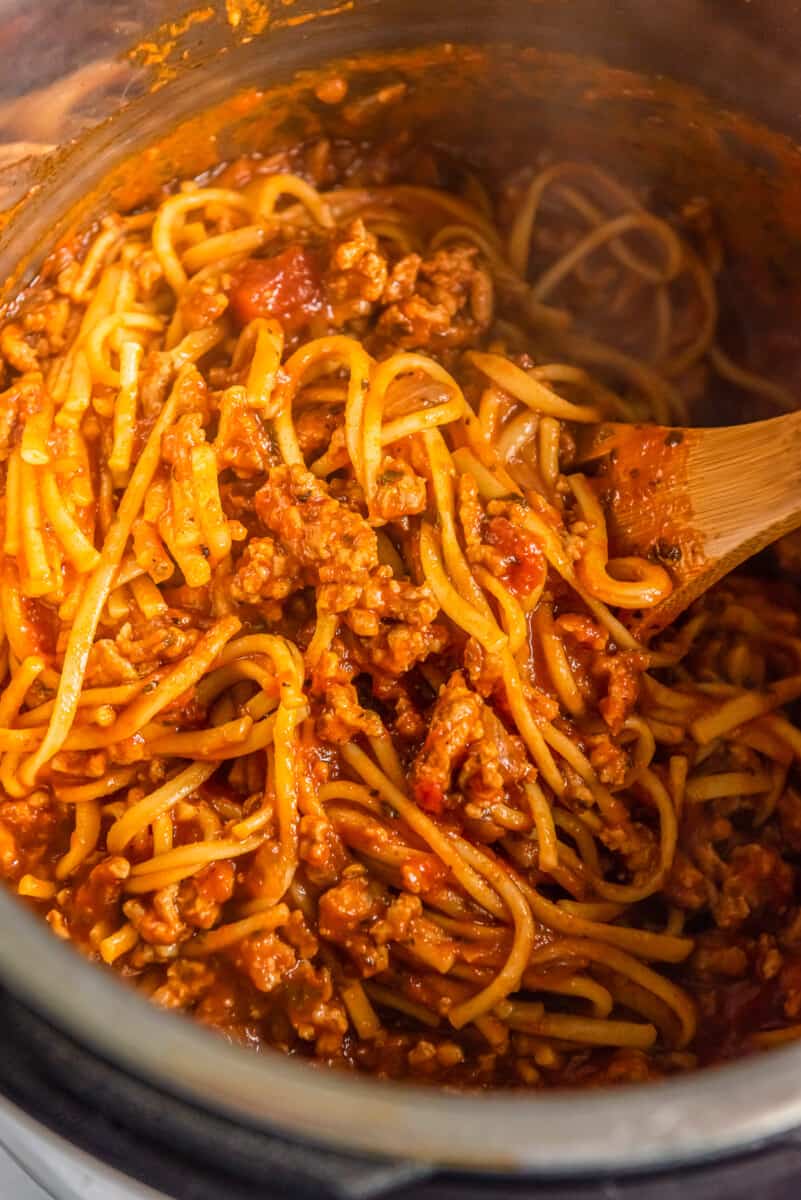 spaghetti with Italian sausage sauce in instant pot with wood spoon