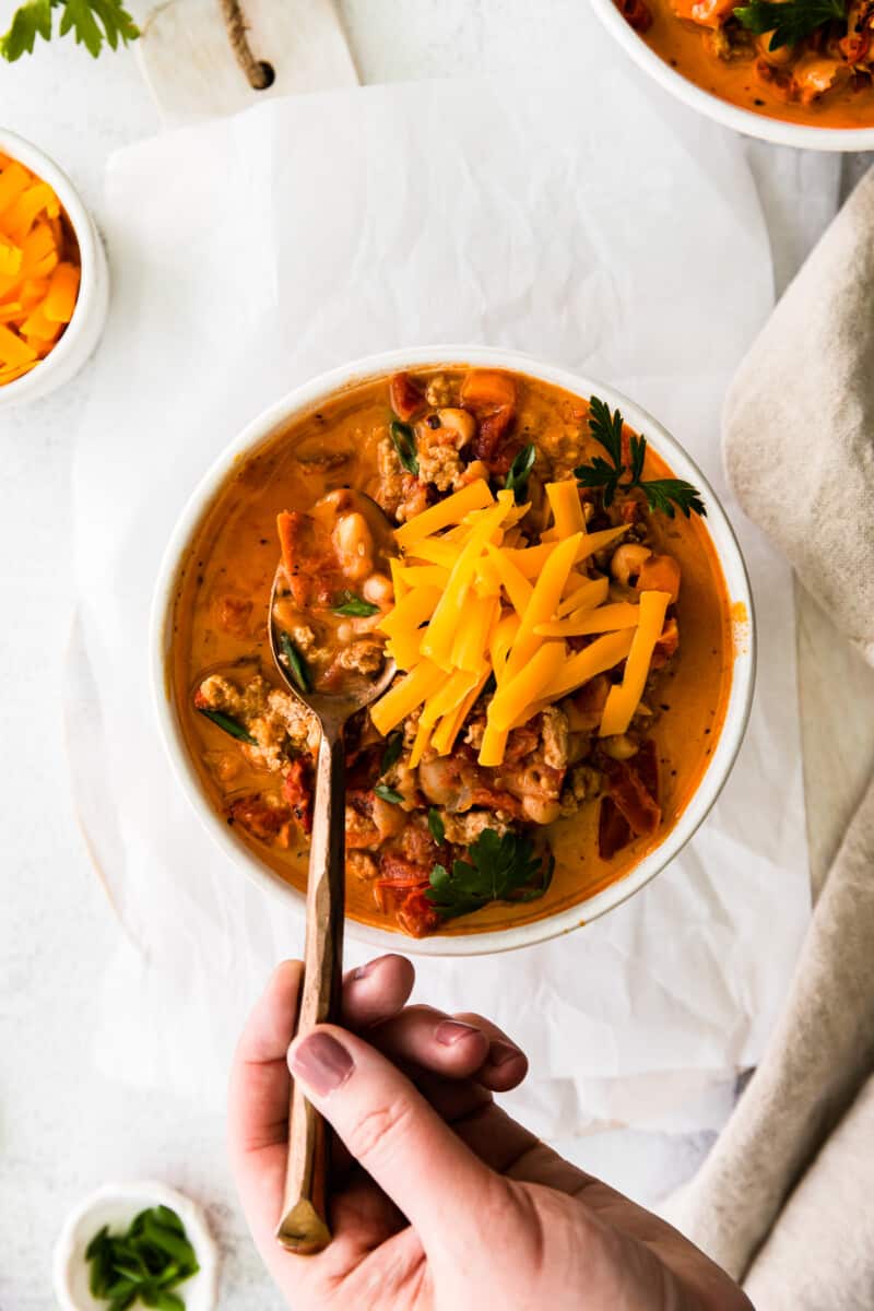 hand holding a spoon in a bowl of turkey white bean chili