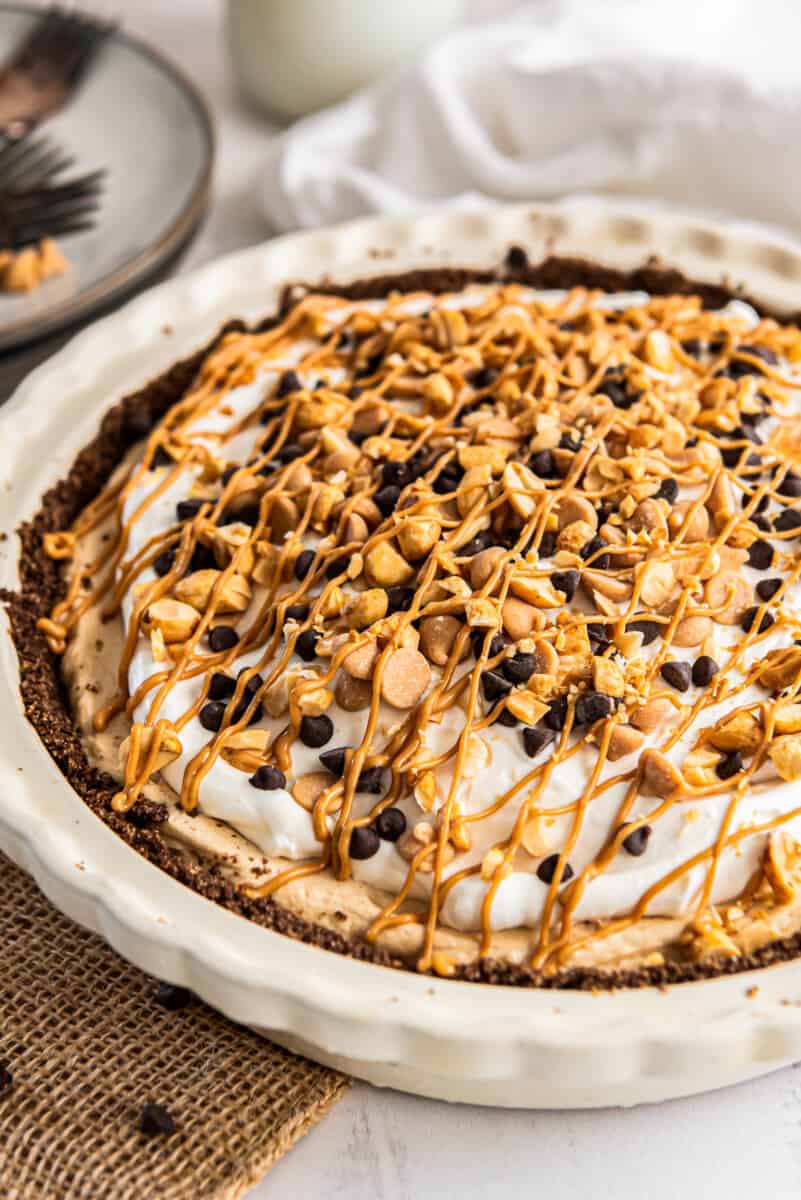 peanut butter pie topped with whipped cream, melted peanut butter, chocolate chips, and peanut butter chips