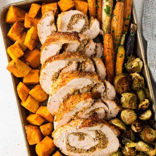 roasted sweet potatoes, carrots, and Brussels sprouts and sliced turkey roulade on a sheet pan
