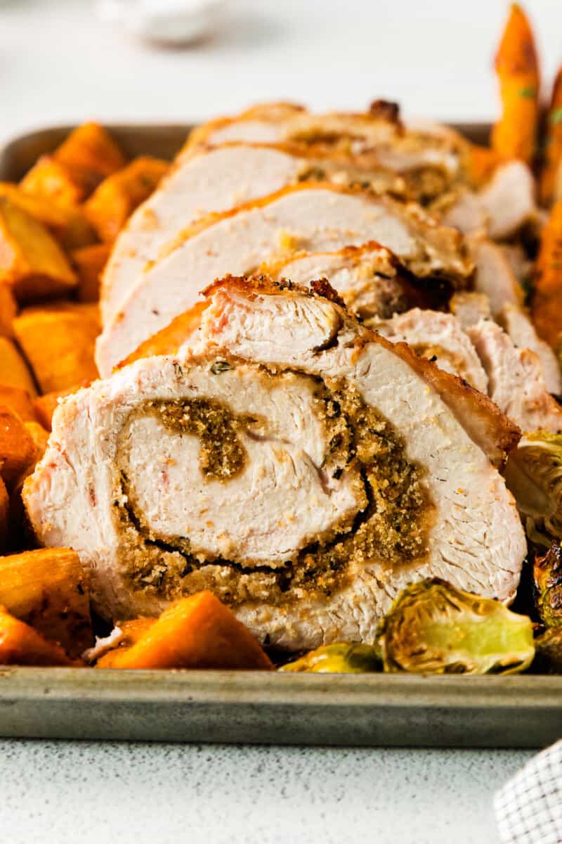 roasted sweet potatoes, carrots, and Brussels sprouts and sliced turkey roulade on a sheet pan