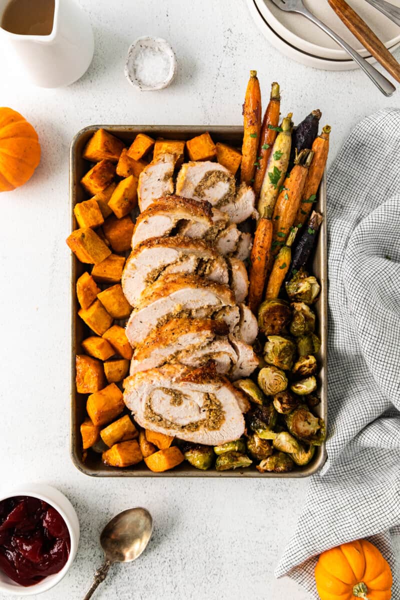 roasted sweet potatoes, carrots, and Brussels sprouts and sliced turkey roulade on a sheet pan