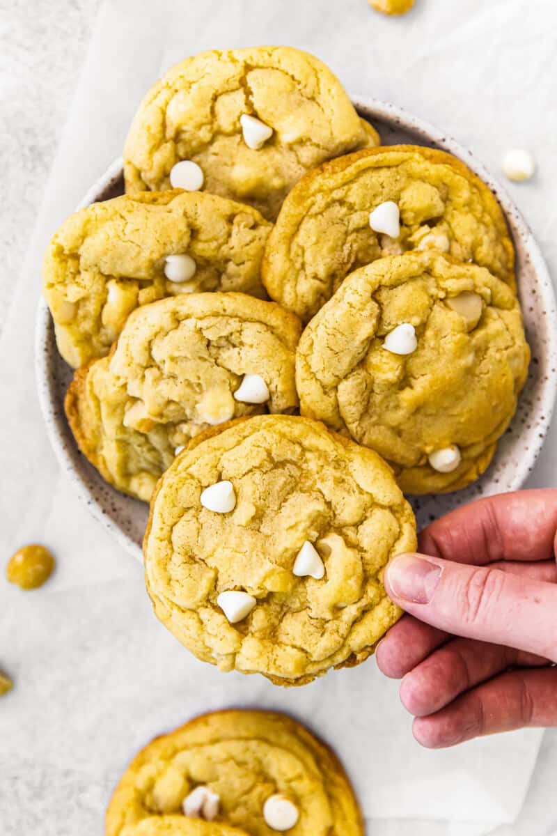 holding up white chocolate macadamia nut cookie with hand