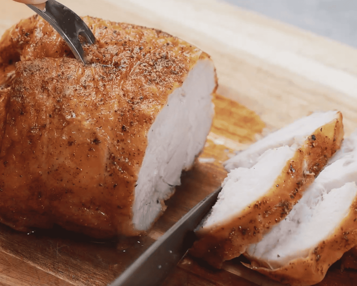 Sliced deep-fried turkey breast on a cutting board, showing golden-brown crispy skin and juicy white meat.