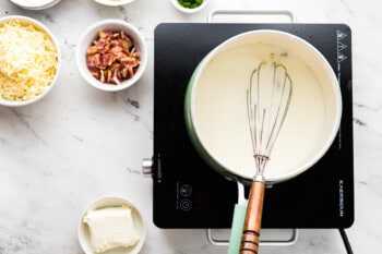 cooked roux for loaded cauliflower bake in a saucepan with a whisk.