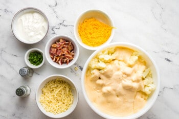 loaded cauliflower bake sauce poured over cauliflower in a white bowl.