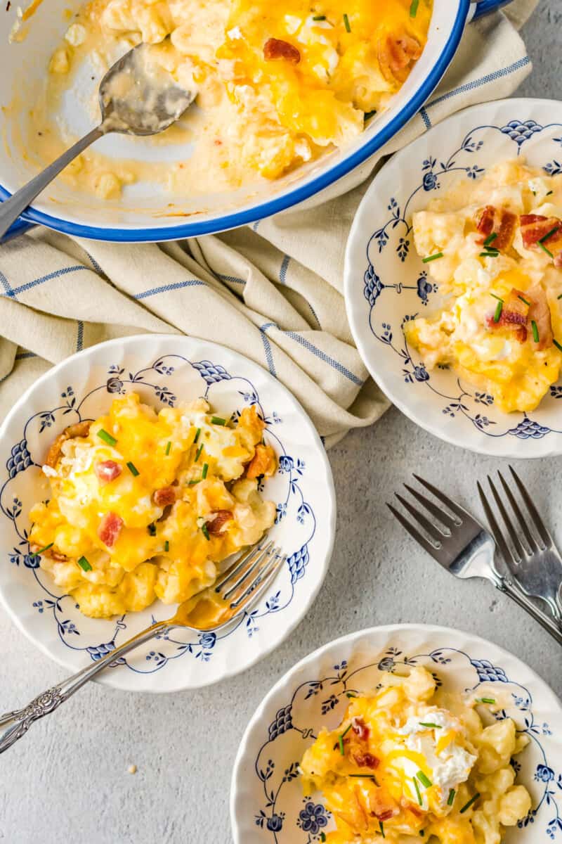 overhead view of loaded cauliflower bake in decorative white bowls with forks.