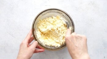 hands mixing cheese filling in a glass bowl for stuffed shells