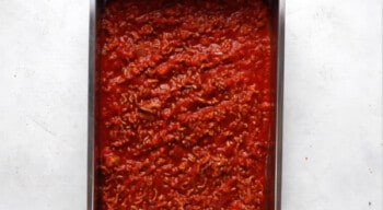meat marinara sauce in the bottom of a baking dish