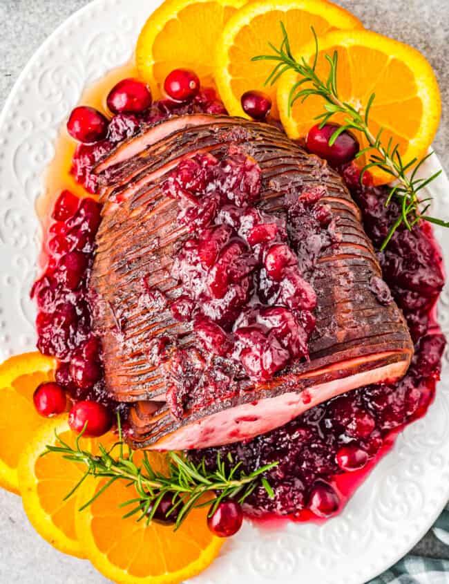 overhead image of cranberry glazed ham on a white serving platter