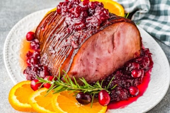 cranberry glazed ham on a white serving platter