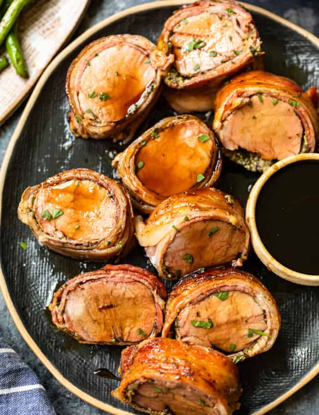 slices of bacon wrapped pork tenderloin on a serving plate