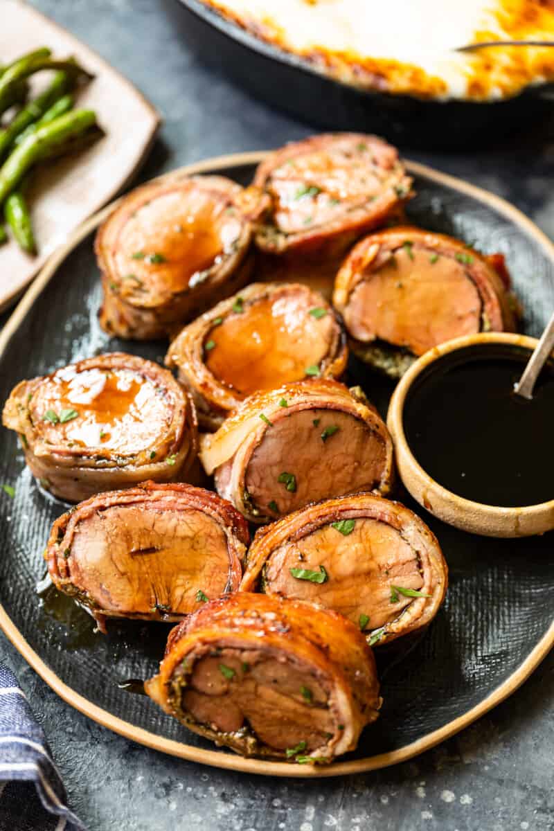 slices of bacon wrapped pork tenderloin on a serving plate