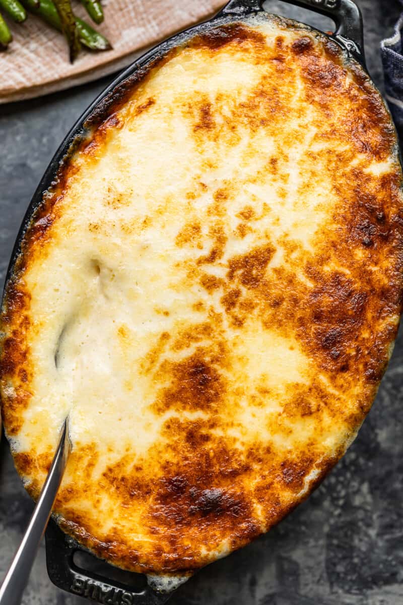 overhead image of chantilly potatoes in a baking dish with a serving spoon