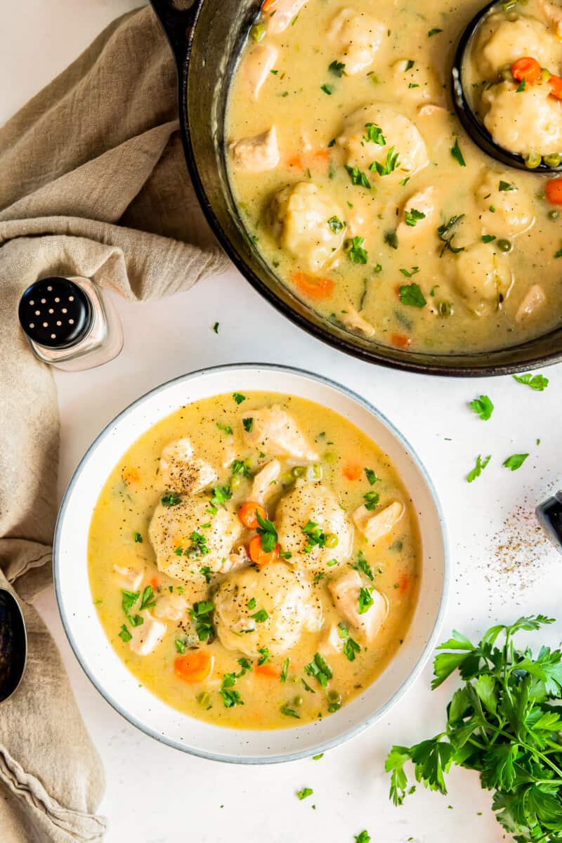 overhead image of chicken and dumplings in a white bowl and in a saucepan